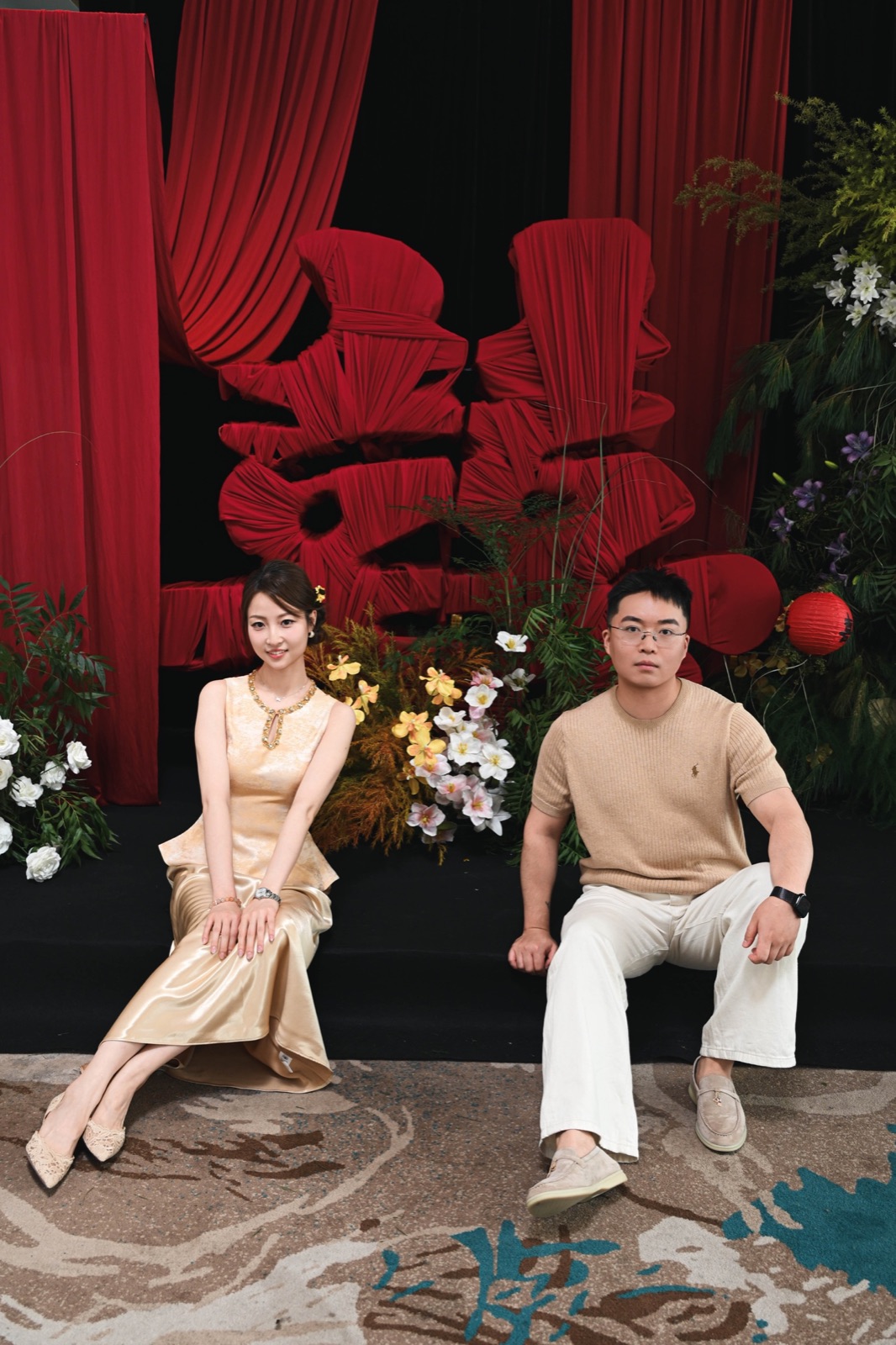 两人在红色喜字花艺前的完整坐姿合影